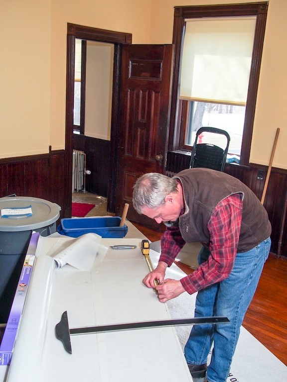 Preservationist craftsman Steve Elkins works on UV protective film for placement in a 3rd floor window.