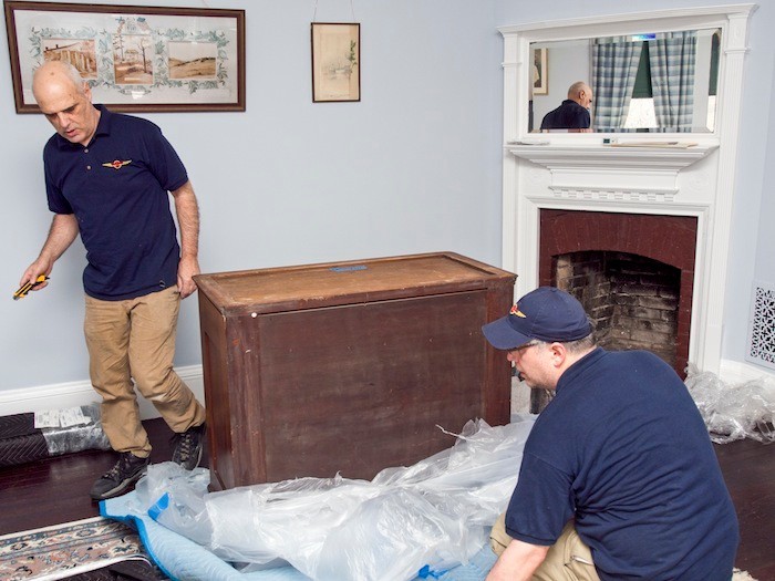 workers from U.S.Art unwrapping a mahogany chest for setup in the "Gate Room" on the 2nd floor.